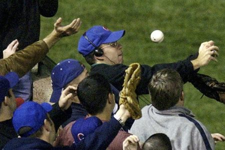 In this Oct. 14, 2003 file photo, Chicago Cubs left fielder Moises Alou's arm is seen reaching into the stands, at right, unsuccessfully for a foul ball along with a fan identified as Steve Bartman, left, wearing headphones, glasses and Cubs hat, during the eighth inning against the Florida Marlins in Game 6 of the National League Championship Seriesin Chicago.