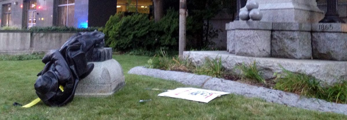 A toppled Confederate statue lies on the ground