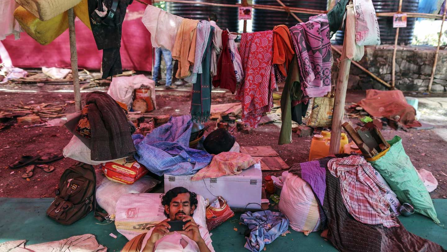 A man watches a film on a smartphone inside a temporary suburban camp, set up by local political party Shiv Sena for the rural poor traveling to Mumbai to find water, in Thane, Maharashtra, India, on Sunday, April 17, 2016. (Dhiraj Singh/Bloomberg via Getty Images)