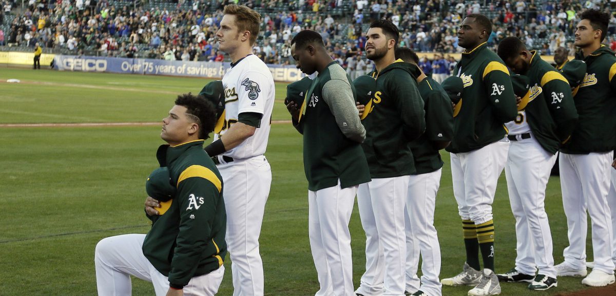 Oakland Athletics catcher Bruce Maxwell kneels during the national anthem before the start of a baseball game against the Texas Rangers Saturday, Sept. 23, 2017, in Oakland, Calif. Bruce Maxwell of the Oakland Athletics has become the first major league baseball player to kneel during the national anthem. (AP Photo/Eric Risberg)