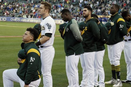 Oakland Athletics catcher Bruce Maxwell kneels during the national anthem before the start of a baseball game against the Texas Rangers Saturday, Sept. 23, 2017, in Oakland, Calif. Bruce Maxwell of the Oakland Athletics has become the first major league baseball player to kneel during the national anthem. (AP Photo/Eric Risberg)