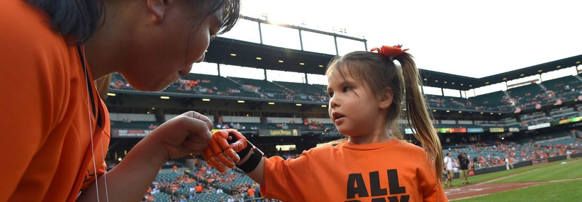 Yong Dawson, left, gives her daughter Hailey Dawson, 5, a fist bump before Hailey throws the ceremonial first pitch before a game between the MLB Teams Baltimore Orioles and Oakland Athletics on Monday, Aug. 17, 2015, at Camden Yards in Baltimore.