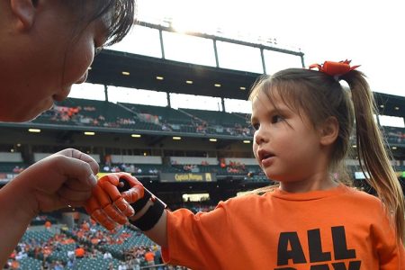 Yong Dawson, left, gives her daughter Hailey Dawson, 5, a fist bump before Hailey throws the ceremonial first pitch before a game between the MLB Teams Baltimore Orioles and Oakland Athletics on Monday, Aug. 17, 2015, at Camden Yards in Baltimore.