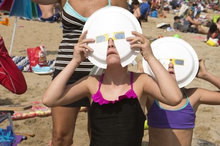 Members of two vacationing families observe the partial solar eclipse at through some hand-improved solar glasses fat Old Orchard Beach. From left: Paul Scango, Katie Vanlandingham (cq), Samantha Scango, Avery Vanlandingham and Quinn Vanlandingham. (Ben McCanna/Portland Press Herald via Getty Images)