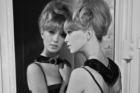 1964: Patti Boyd in a bare-shouldered evening dress and an elaborate bead necklace leans wistfully against a full-length mirror. (Photo by Chaloner Woods/Getty Images)