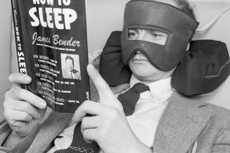 A retailing store of singular distinction is the Lewis & Conger Sleep Shop. An insomniac's paradise, the shop is the only one of its kind in the world, selling items devoted exclusively to wooing comfort in bed and good old sleep. Television comic Wally Cox, who is sometimes troubled with uneasy slumberings (even as you and I), was caught trying out some of the newest bedtime innovations. Photo shows: Wally Cox catches up on some pertinent readings while wearing an electric facial mask that soothes aches and pains with gentle heat. His head rests on a neck pillow that props and supports the head for reading at a good angle.