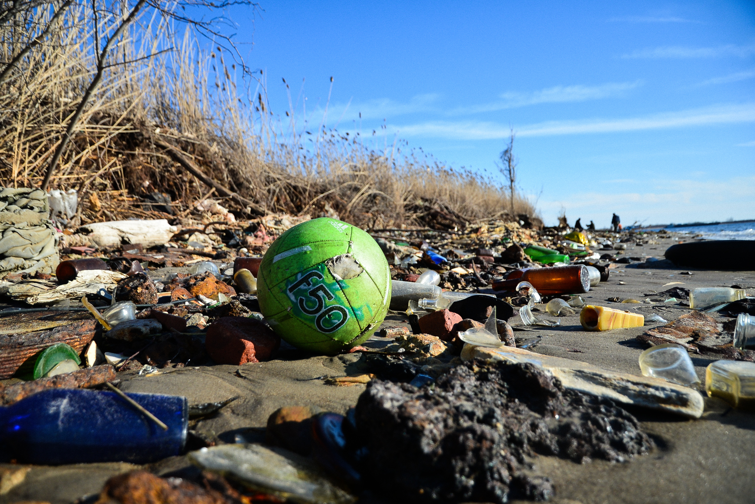 A soccer ball, broken bottles and other trash wash ashore at Dead Horse Bay. March 11, 2018. (Diana Crandall)