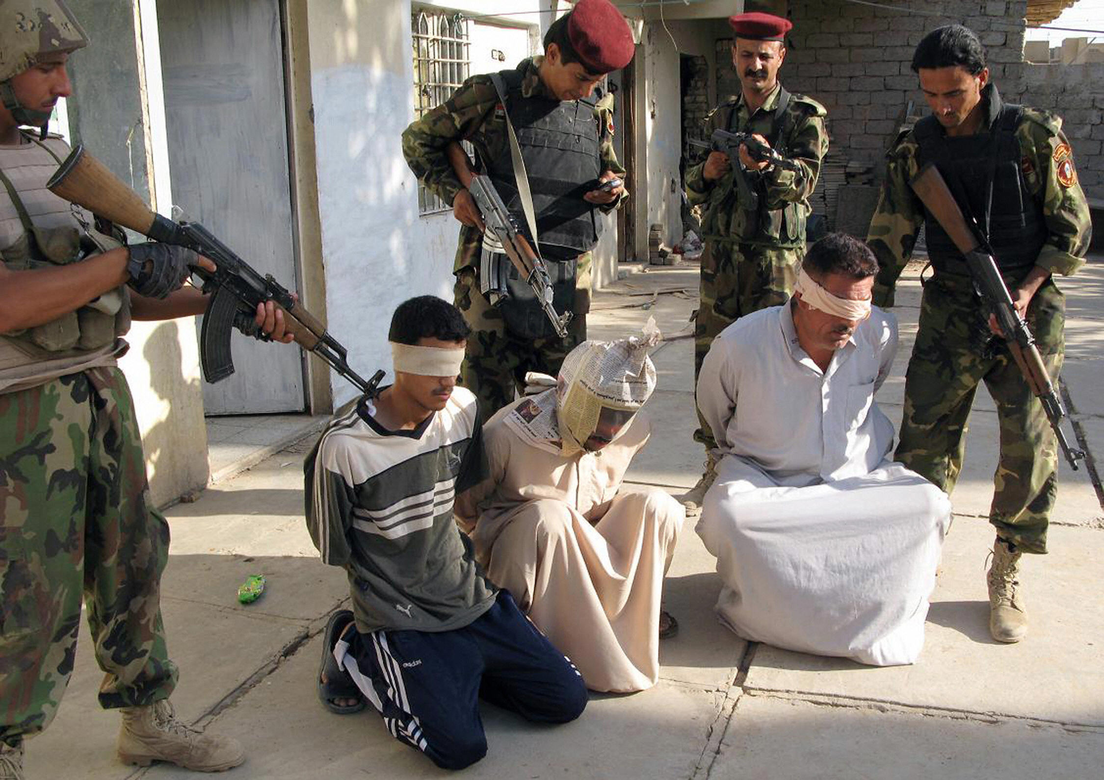 Iraqi soldiers guard blindfolded suspects at a military detention centre in the restive city of Baquba, in Diyala province, northeast of Baghdad, 30 June 2007. (STR/AFP/Getty Images)