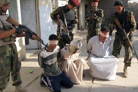 Iraqi soldiers guard blindfolded suspects at a military detention centre in the restive city of Baquba, in Diyala province, northeast of Baghdad, 30 June 2007. (STR/AFP/Getty Images)