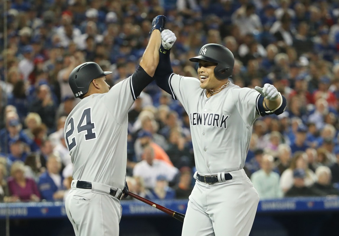 Giancarlo Stanton #27 of the New York Yankees is congratulated by Gary Sanchez #24 after hitting a two-run home run in the first inning on Opening Day during MLB game action against the Toronto Blue Jays at Rogers Centre on March 29, 2018 in Toronto, Canada. (Photo by Tom Szczerbowski/Getty Images)