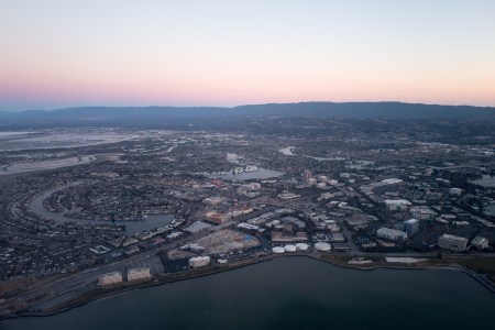Aerial view of Silicon Valley at dusk, with a portion of the San Mateo/Hayward Bridge visible, as well as Foster City, including the California headquarters of Gilead Sciences, Visa, and Conversica, California, July, 2016. (Photo by Smith Collection/Gado/Getty Images).