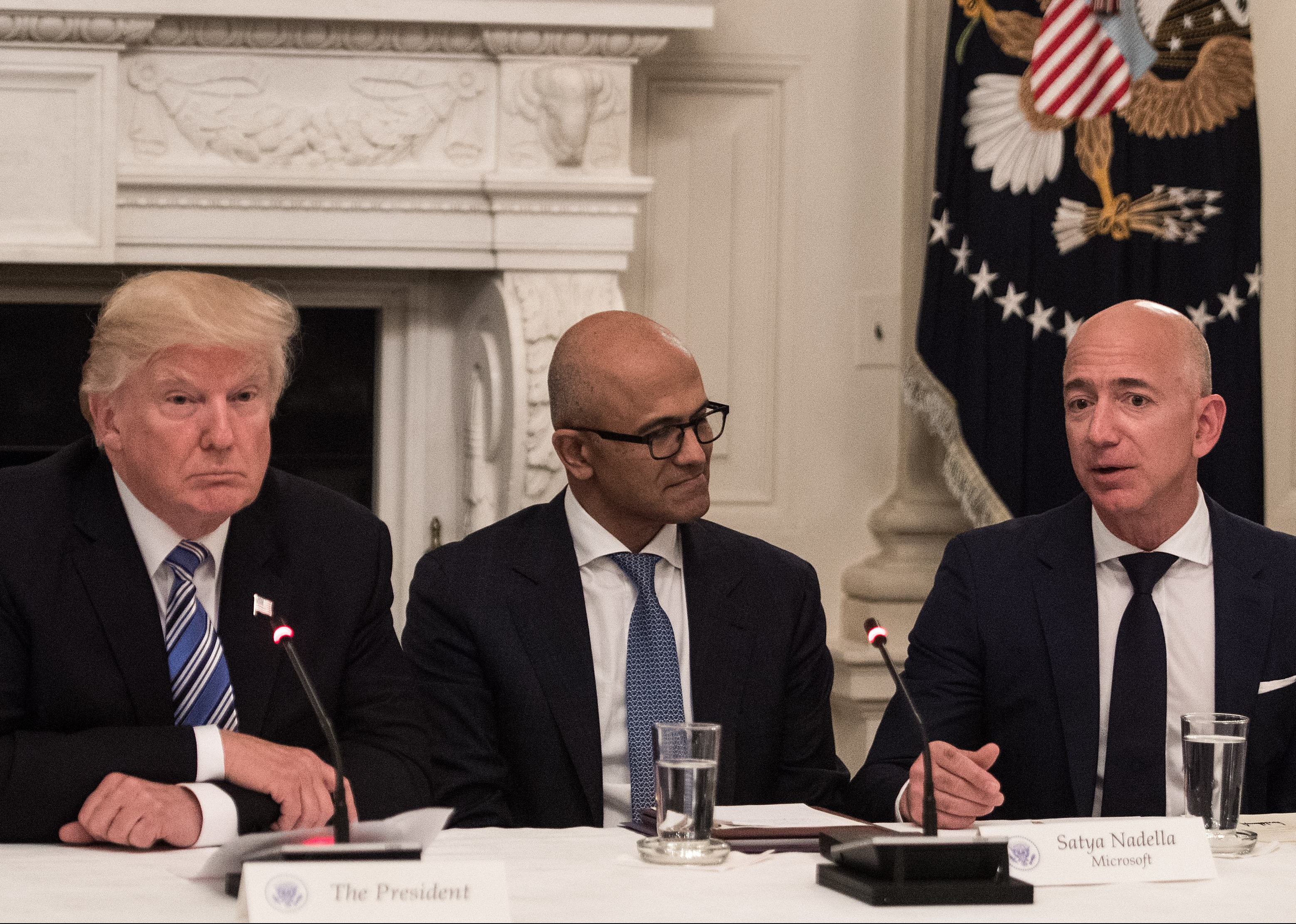 US President Donald Trump (L) and Microsoft CEO Satya Nadella (C) listen to Amazon CEO Jeff Bezos (R) during an American Technology Council roundtable at the White House in Washington, DC, on June 19, 2017. / AFP PHOTO / NICHOLAS KAMM        (Photo credit should read NICHOLAS KAMM/AFP/Getty Images)