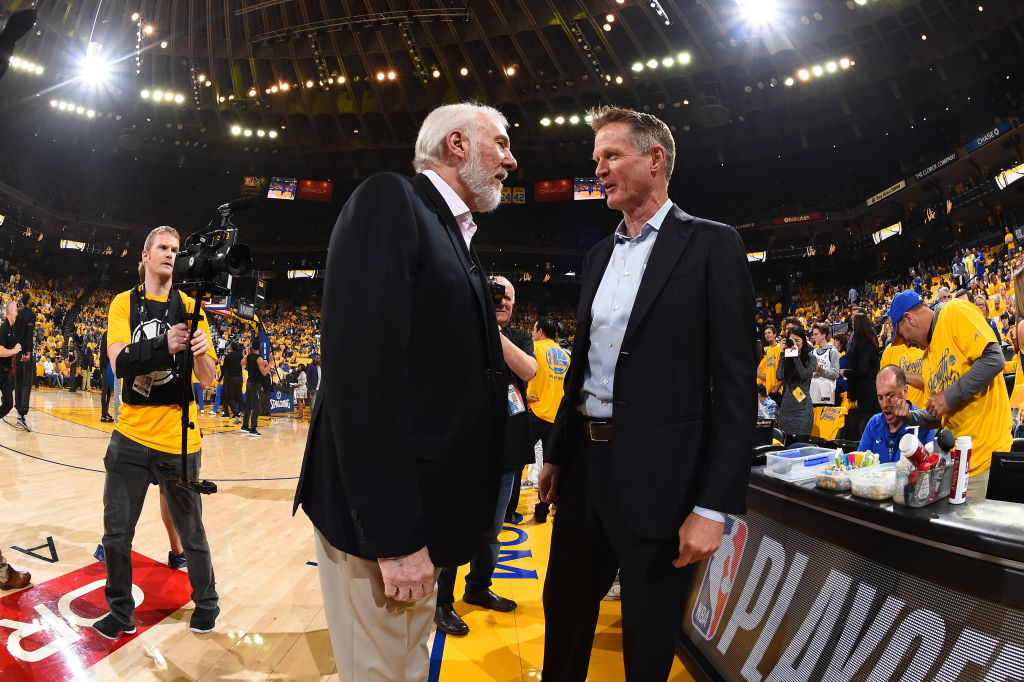 Head Coach Steve Kerr of the Golden State Warriors and Head Coach Gregg Popovich of the San Antonio Spurs speak before the game in Game One of Round One during the 2018 NBA Playoffs on April 14, 2018 at ORACLE Arena in Oakland, California. NOTE TO USER: User expressly acknowledges and agrees that, by downloading and or using this photograph, user is consenting to the terms and conditions of Getty Images License Agreement. Mandatory Copyright Notice: Copyright 2018 NBAE (Photo by Andrew D. Bernstein/NBAE via Getty Images)