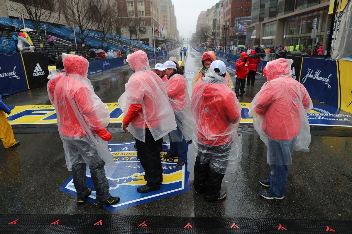 Volunteers in rain gear stand at the Boston Marathon finish line in Boston on April 16, 2018. (Photo by John Tlumacki/The Boston Globe via Getty Images)