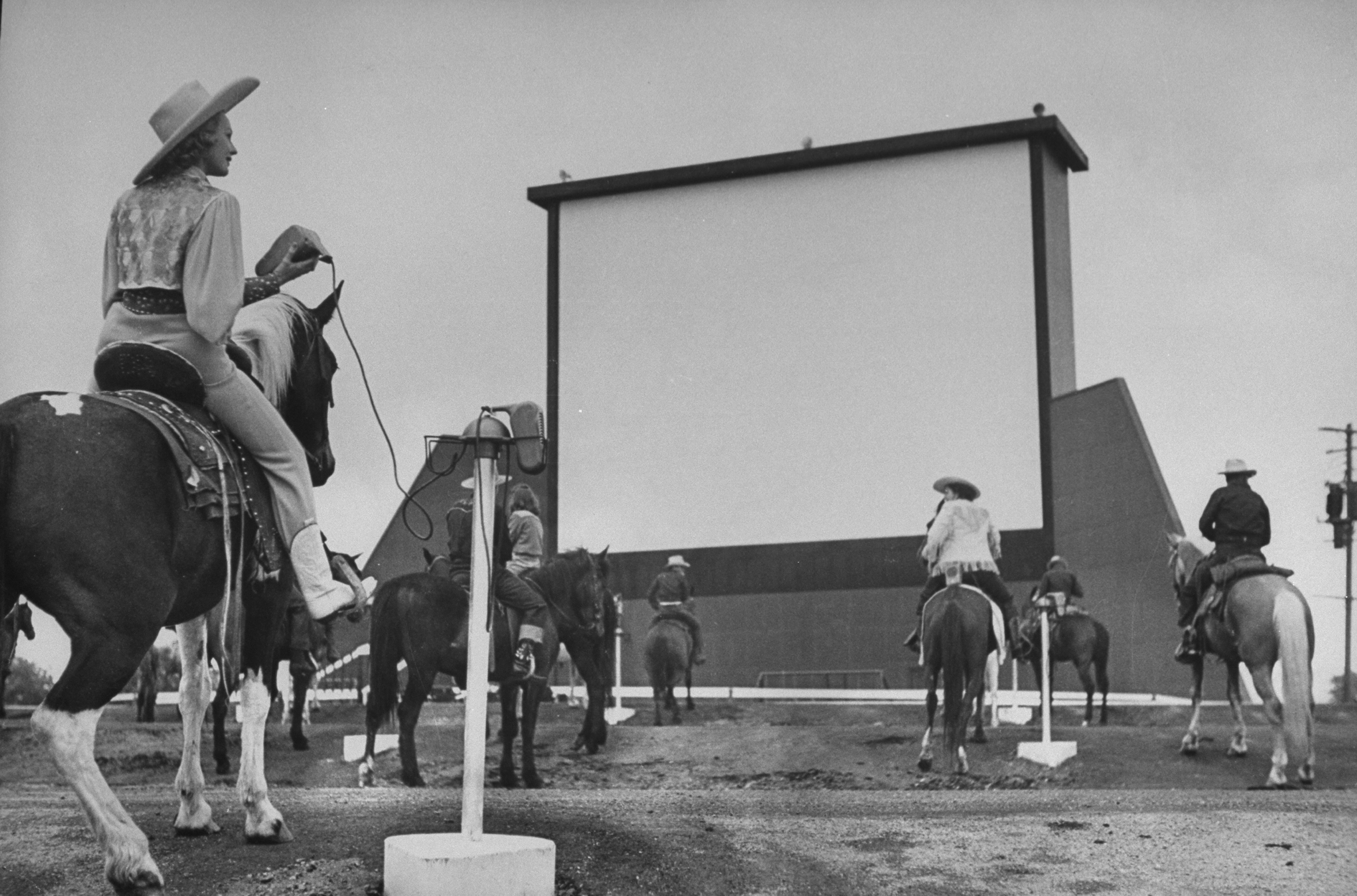 Horseback riders in cowboy garb, taking positions at speaker posts while settling in to watch the evening's feature at a Drive-In movie theater.  (Photo by Carl Iwasaki/The LIFE Images Collection/Getty Images)
