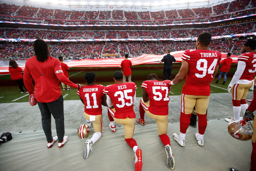 Eli Harold #57, Eric Reid #35 and Marquise Goodwin #11 of the San Francisco 49ers kneel on the sideline, during the anthem, prior to the game against the Seattle Seahawks at Levi's Stadium on November 26, 2017 in Santa Clara, California. The Seahawks defeated the 49ers 24-13. (Photo by Michael Zagaris/San Francisco 49ers/Getty Images)