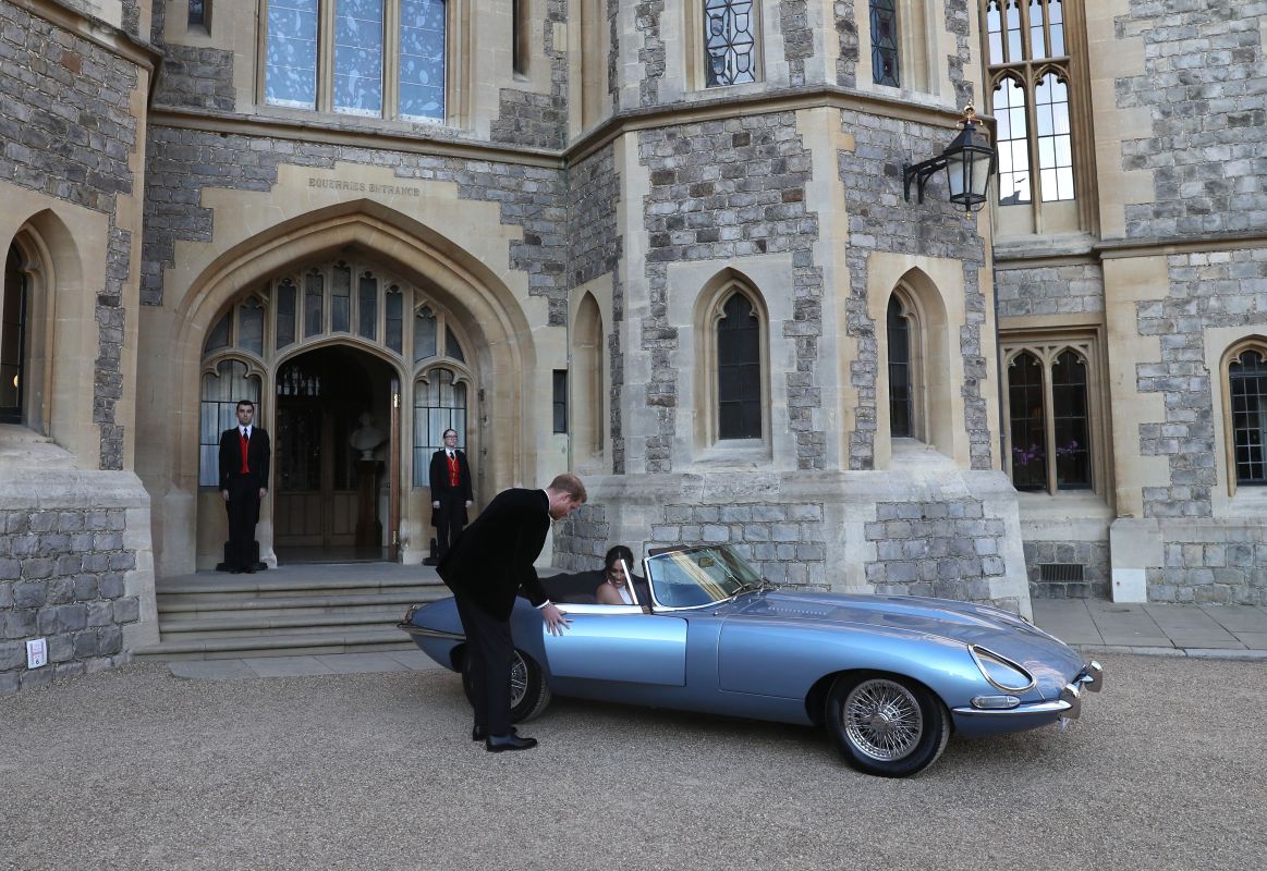 Britain's Prince Harry, Duke of Sussex, (L) opens the passenger door of an E-Type Jaguar car for his wife Meghan Markle, Duchess of Sussex, (R) as they leave Windsor Castle in Windsor on May 19, 2018 after their wedding to attend an evening reception at Frogmore House. (Steve Parsons / POOL / AFP)        (Photo credit should read STEVE PARSONS/AFP/Getty Images)