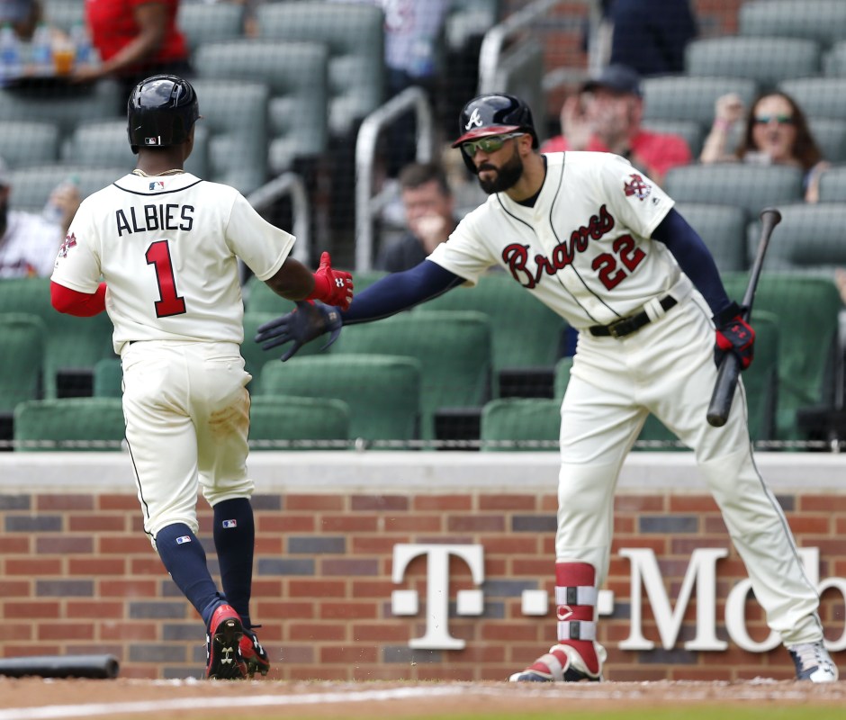 Ozzie Albies #1 of the Atlanta Braves is congratulated by Nick Markakis #22 after Albies scored in the ninth inning during the game against  the Miami Marlins at SunTrust Park on May 20, 2018 in Atlanta, Georgia.  (Photo by Mike Zarrilli/Getty Images)
