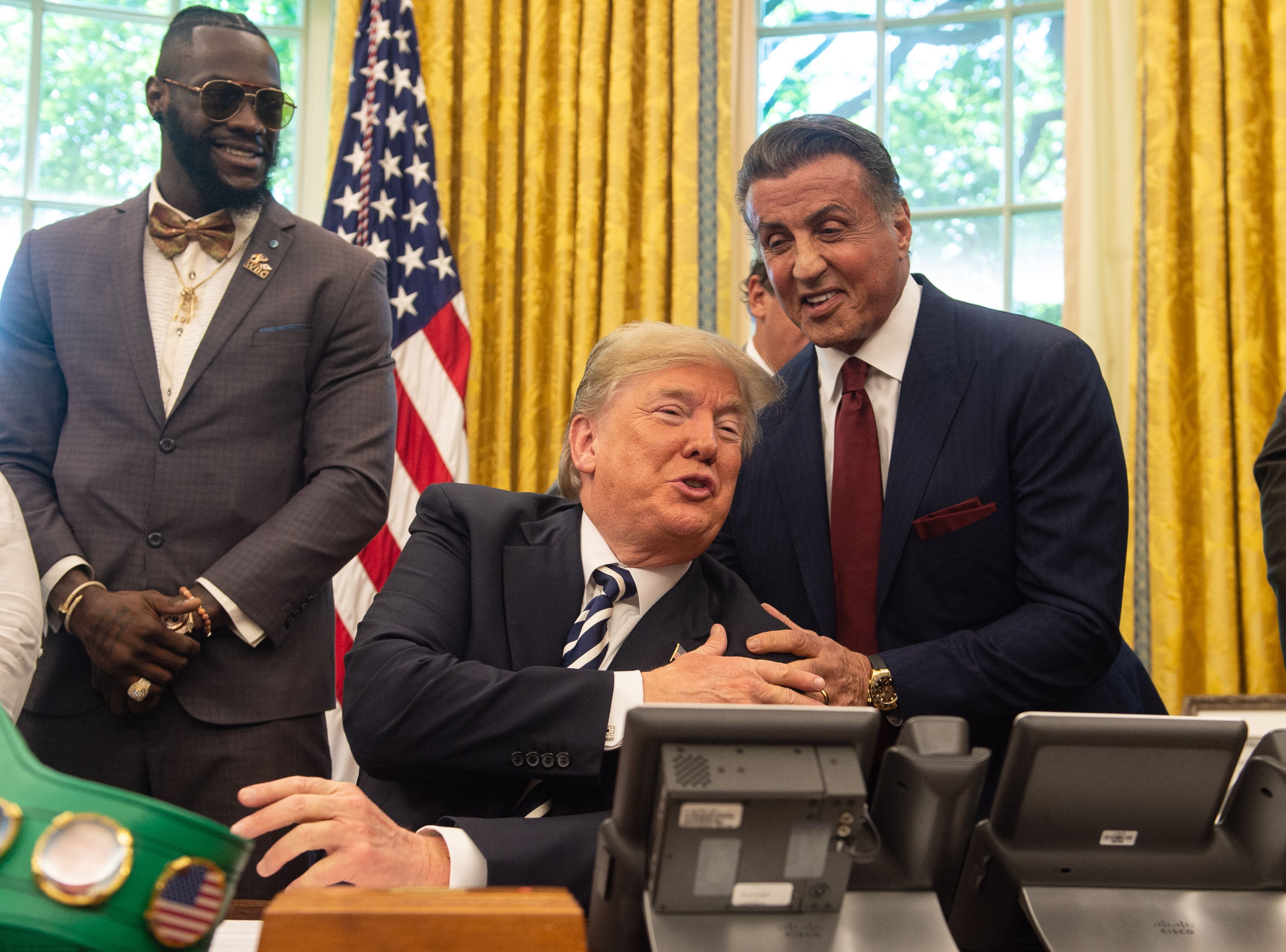 President Donald Trump jokes with actor Sylvester Stallone(R) before signing a posthumous pardon for former world champion boxer Jack Johnson in the Oval Office at the White House in Washington, DC, on May 24, 2018, as boxer Lennox Lewis looks on. (NICHOLAS KAMM / AFP/Getty)  