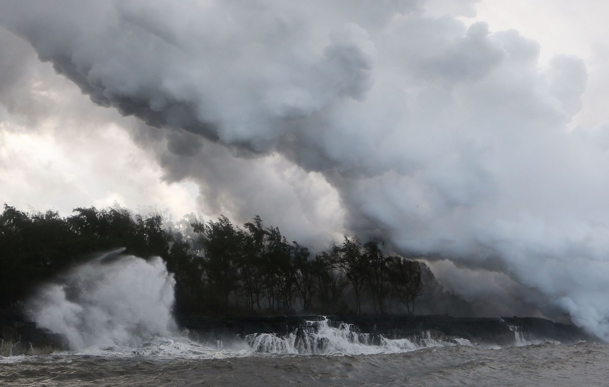 Steam and volcanic gases rise (R) as lava enters the Pacific Ocean, after flowing to the water from a Kilauea volcano fissure, on Hawaii's Big Island on May 20, 2018 near Pahoa, Hawaii. Officials are concerned that 'laze', a dangerous product produced when hot lava hits cool ocean water, will affect residents. Laze, a word combination of lava and haze, contains hydrochloric acid steam along with volcanic glass particles.  (Photo by Mario Tama/Getty Images)
