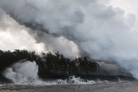 Steam and volcanic gases rise (R) as lava enters the Pacific Ocean, after flowing to the water from a Kilauea volcano fissure, on Hawaii's Big Island on May 20, 2018 near Pahoa, Hawaii. Officials are concerned that 'laze', a dangerous product produced when hot lava hits cool ocean water, will affect residents. Laze, a word combination of lava and haze, contains hydrochloric acid steam along with volcanic glass particles.  (Photo by Mario Tama/Getty Images)