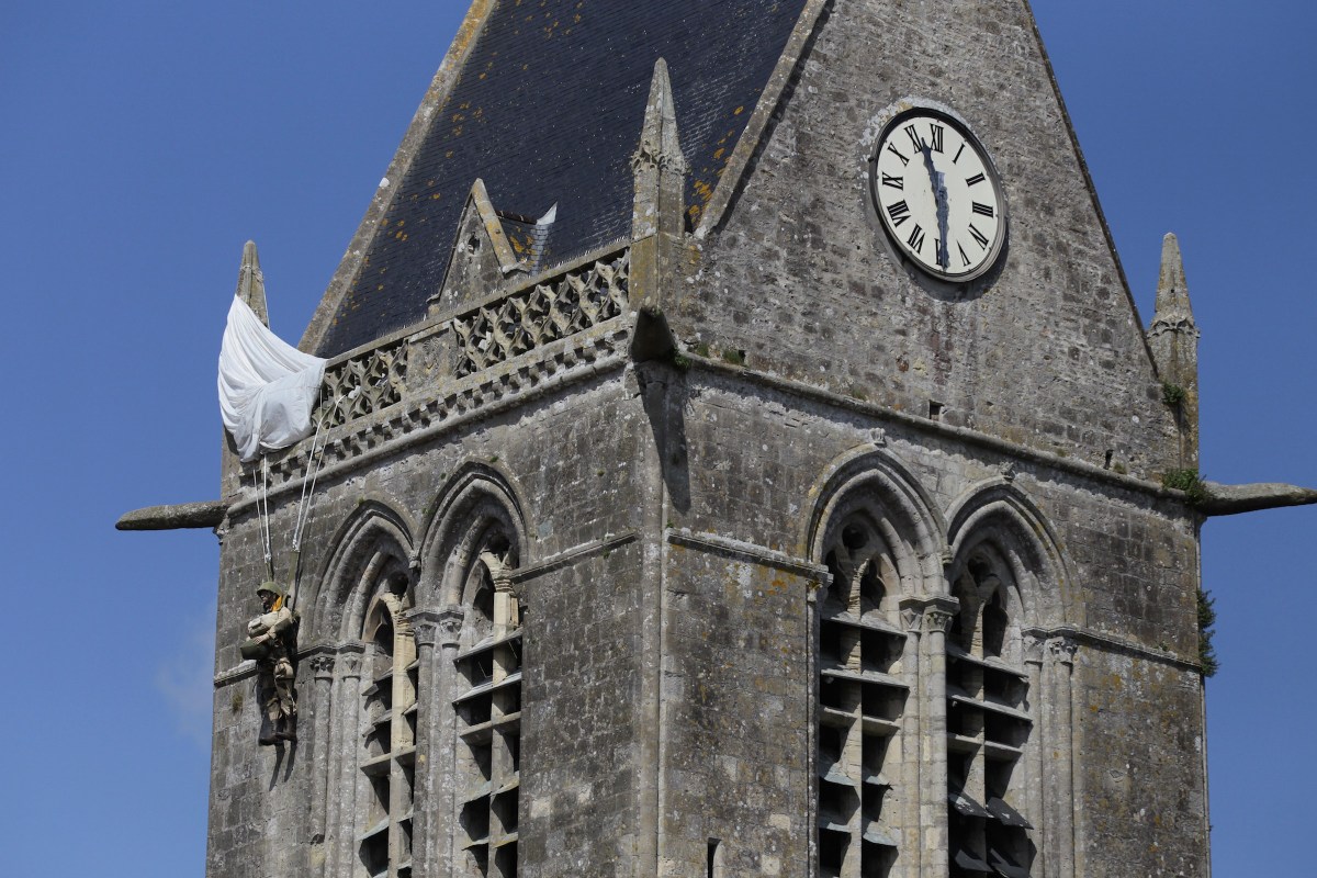 This picture taken on May 31, 2014 shows an effigy of a paratrooper hung on the bell tower of the Sainte-Mere-Eglise church in memory of Private John Steele who found himself hanging on the church tour on June 5, 1944 during Operation Overlord, in Sainte-Mere-Eglise, northwestern France.  (AFP PHOTO/CHARLY TRIBALLEAU) 