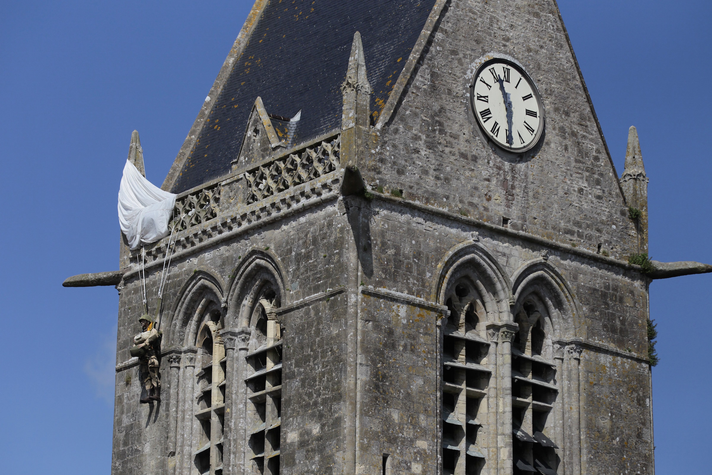 This picture taken on May 31, 2014 shows an effigy of a paratrooper hung on the bell tower of the Sainte-Mere-Eglise church in memory of Private John Steele who found himself hanging on the church tour on June 5, 1944 during Operation Overlord, in Sainte-Mere-Eglise, northwestern France. (AFP PHOTO/CHARLY TRIBALLEAU)