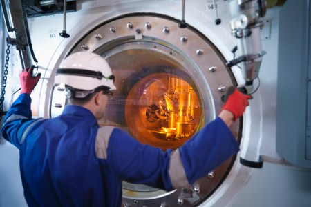 Engineer with fuel rod handling machine in nuclear power station
