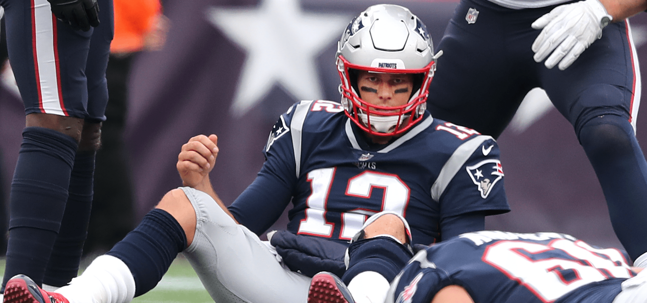 New England Patriots quarterback Tom Brady sits on the field after being sacked during a game against the Houston Texans. (Photo by Jim Davis/The Boston Globe via Getty Images)