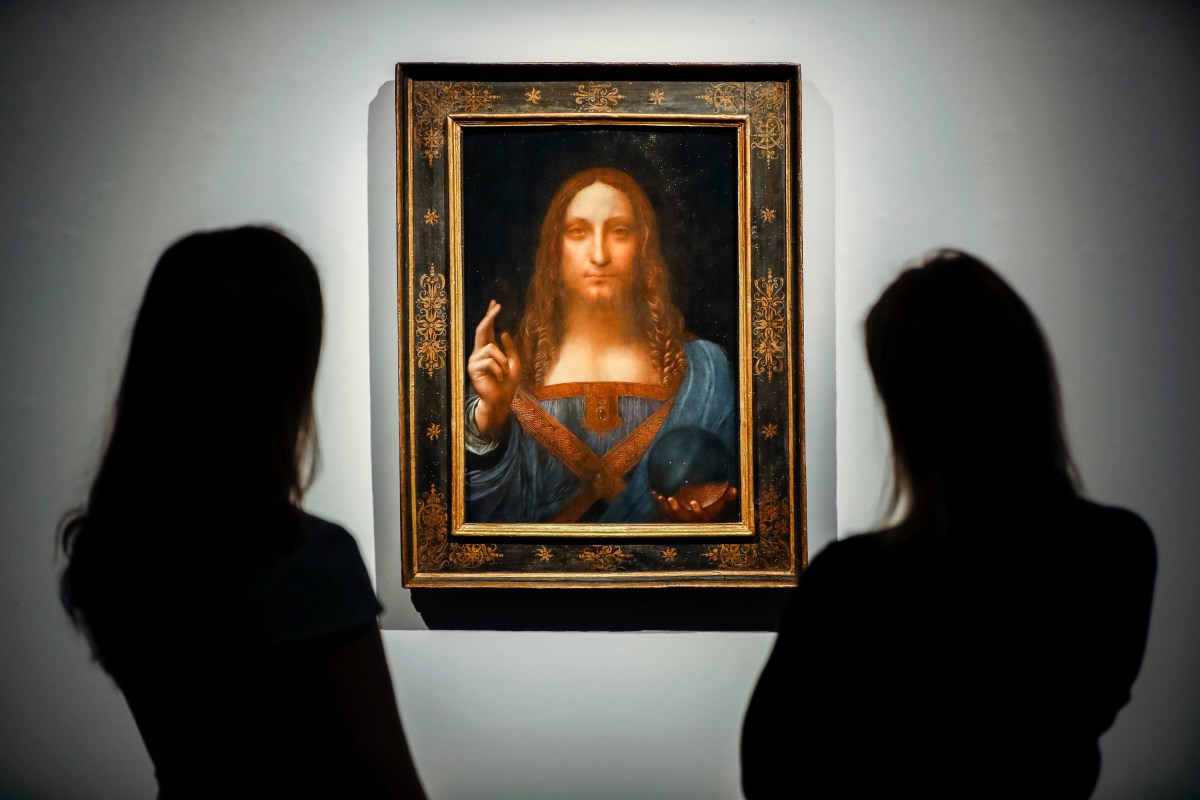 Christie's employees pose in front of Salvator Mundi by Italian polymath Leonardo da Vinci at Christie's auction house in central London on October 22, 2017. The painting was lost in the US for many decades. (Photo by TOLGA AKMEN/AFP/Getty Images).