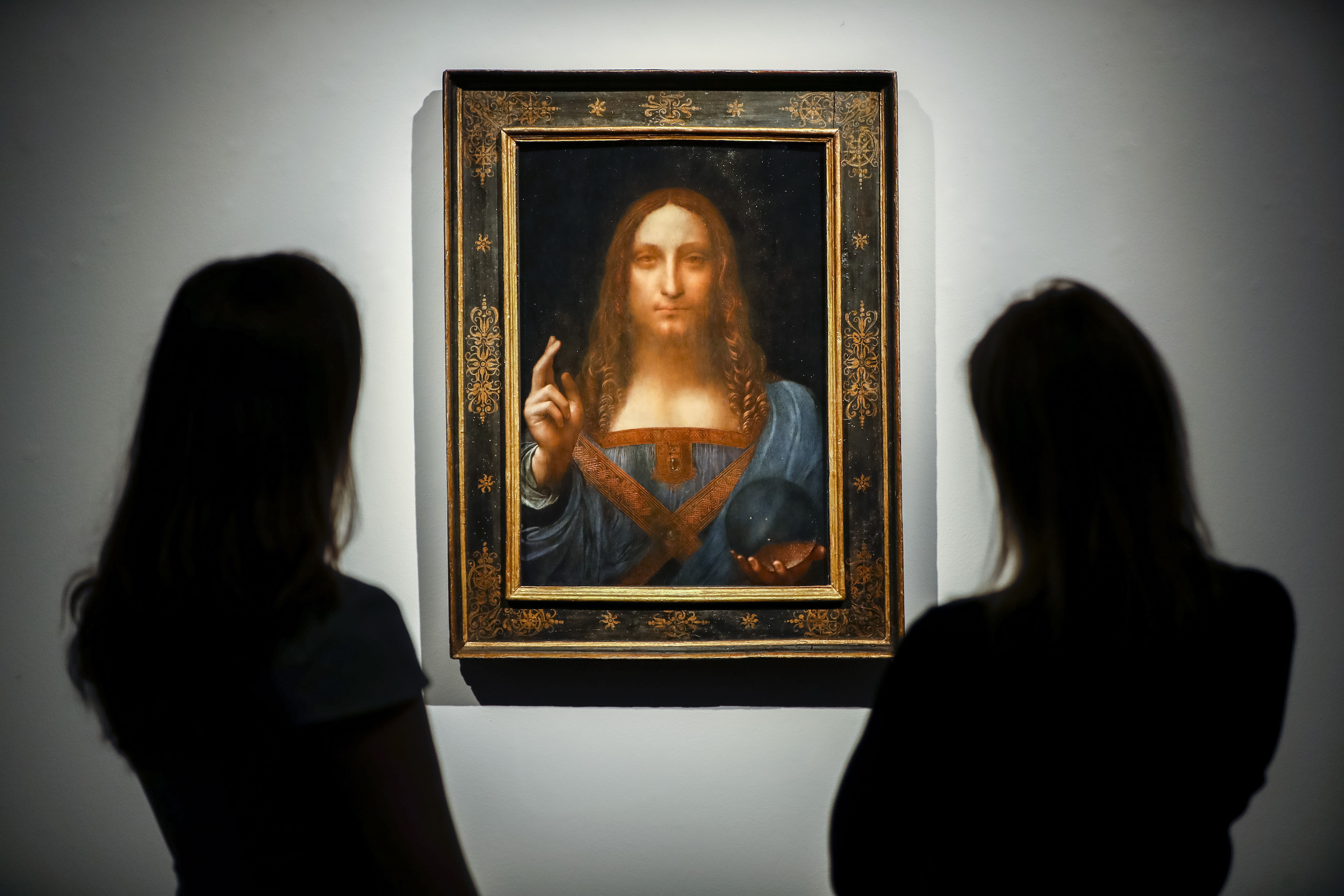Christie's employees pose in front of Salvator Mundi by Italian polymath Leonardo da Vinci at Christie's auction house in central London on October 22, 2017. The painting was lost in the US for many decades. (Photo by TOLGA AKMEN/AFP/Getty Images).