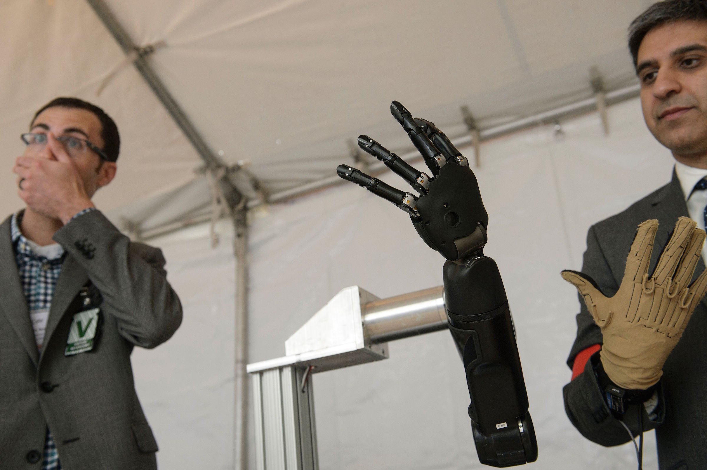Exhibitors from Johns Hopkins Applied Physics Laboratory  stand with a robotic hand during the Defense Advanced Research Projects Agency (DARPA) Demo Day at The Pentagon on May 11, 2016 in Washington, DC. Darpa's continuing research into neurotechnology is currently prompting ethical questions about its potential military applications. (Photo by BRENDAN SMIALOWSKI/AFP/Getty Images)