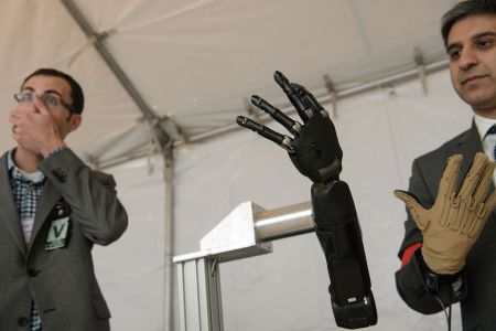 Exhibitors from Johns Hopkins Applied Physics Laboratory  stand with a robotic hand during the Defense Advanced Research Projects Agency (DARPA) Demo Day at The Pentagon on May 11, 2016 in Washington, DC. Darpa's continuing research into neurotechnology is currently prompting ethical questions about its potential military applications. (Photo by BRENDAN SMIALOWSKI/AFP/Getty Images)