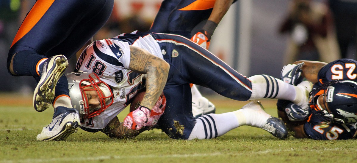 DENVER, CO - DECEMBER 18: Chris Harris #25 of the Denver Broncos tackles Aaron Hernandez #81 of the New England Patriots on December 18, 2011 during the second half at Sports Authority Field at Mile High in Denver, Colorado. (Photo by Marc Piscotty/Getty Images)