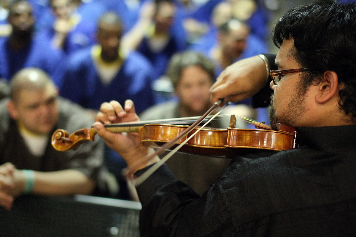 Prison inmates, part of the M.E.R.I.T. (Maximizing Education Reaching Individual Transformation) Program, listen to Vijay Gupta play the violin as part of a summer concert performed by "Street Symphony" at the Men's Central Jail in Los Angeles on August 29, 2012. Gupta recently received a 2018 MacArthur genius grant. (Photo by Gary Friedman/Los Angeles Times/Getty Images)