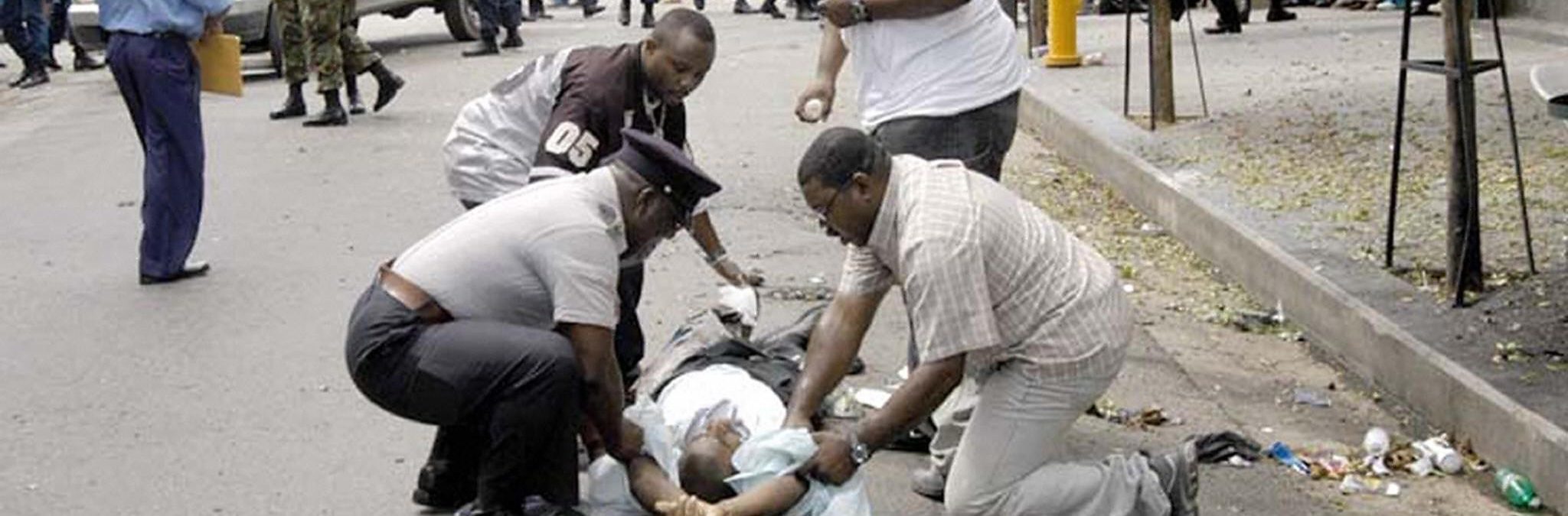 Police and pedestrians help a man wounded 11 July, 2005 after an explosive artifact exploded in a busy shopping district in downtown Port-of-Spain, Trinidad and Tobago, wounding 13 people. Police have yet to confirm if the blast was caused by a bomb or a hand grenade thrown into the bin, as some eyewitness reported. AFP PHOTO STR MAXIMUM QUALITY AVAILABLE TRINIDAD AND TOBAGO OUT (Photo credit should read STR/AFP/Getty Images)