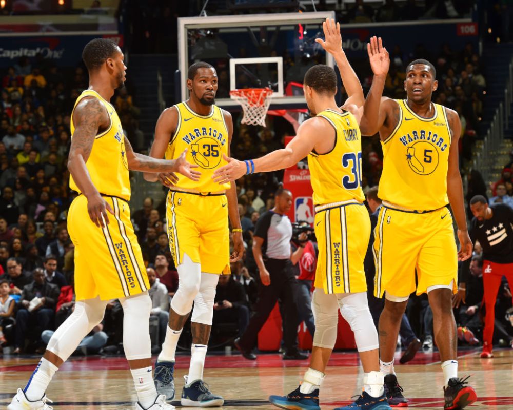 WASHINGTON, DC -  JANUARY 24: Stephen Curry #30 hi-fives Alfonzo McKinnie #28, Kevin Durant #35, and Kevon Looney #5 of the Golden State Warriors on January 24, 2019 at Capital One Arena in Washington, DC. (Photo by Jesse D. GarrabrantNBAE via Getty Images)
