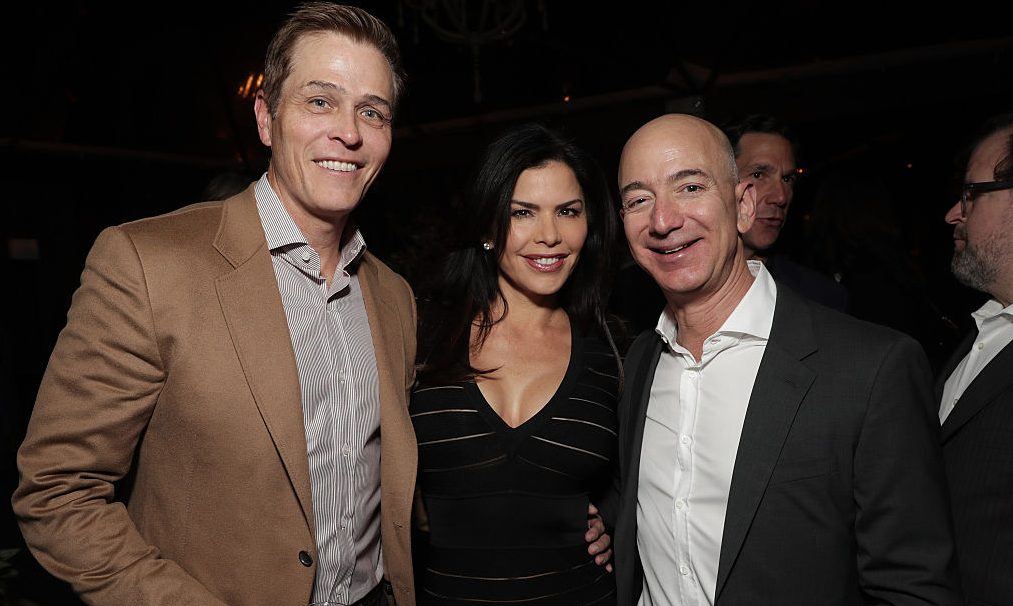 Lauren Sanchez poses with her then-husband Patrick Whitesell (left), and future lover, Amazon CEO Jeff Bezos, at Jeff Bezos and Matt Damon's "Manchester By The Sea" Holiday Party on December 3, 2016 in Los Angeles, California.  (Photo by Todd Williamson/Getty Images for Amazon Studios)