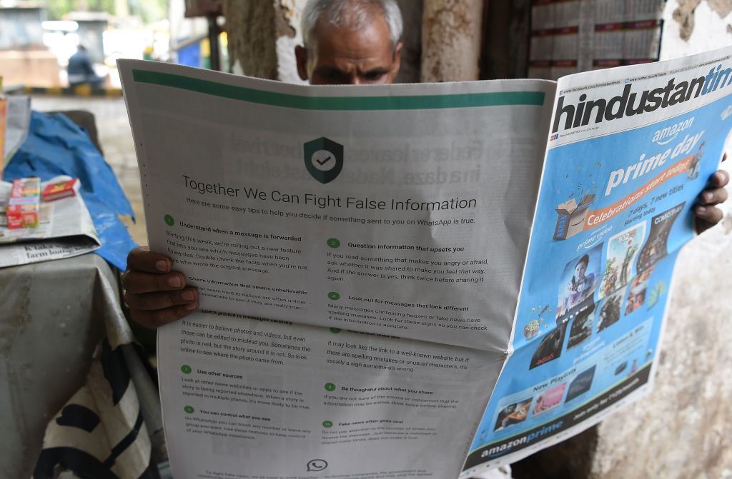 Indian newspaper vendor reading a newspaper with a full back page advertisement from WhatsApp intended to counter fake information, in New Delhi. (Photo credit: Prakash Singh/AFP/Getty Images)