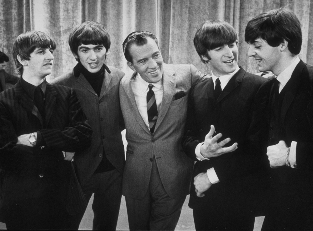 American television host Ed Sullivan smiles while standing with British rock group the Beatles on the set of his television variety series, New York, February 9, 1964. Left to right: Ringo Starr, George Harrison, Sullivan, John Lennon, Paul McCartney. (Photo by Express Newspapers/Getty Images)