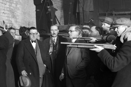 UNITED STATES - FEBRUARY 01: Police reenactment of the St. Valentine's Day Massacre, also known as the Moran Gang Massacre, when reputed members of the Al Capone gang disguised themselves as policemen and murdered members of the George 'Bugs' Moran gang in a garage at 2122 North Clark Street in the Lake View community area of Chicago, Illinois. Dr. Herman N. Bundesen, Cook County Coroner, is standing next to the men holding the rifles. (Photo by Chicago Sun-Times/Chicago Daily News collection/Chicago History Museum/Getty Images)