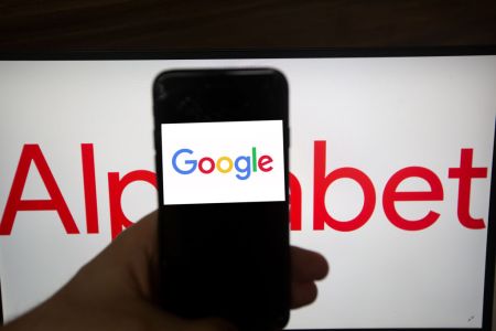 The logo of Google is seen on a screen. In the background there is the logo of Alphabet. Alphabet is the mother company of Google. It has a revenue of 117 billion dollars. (Photo by Alexander Pohl/NurPhoto via Getty Images)