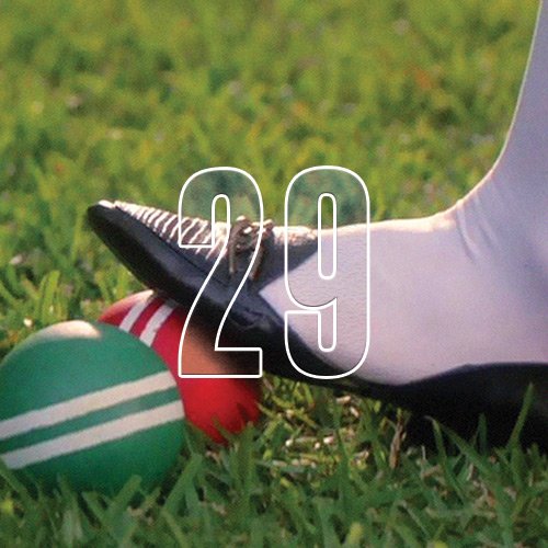A person's foot stepping on two cricket balls, with an overlay of the number "29"
