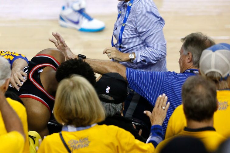 Kyle Lowry #7 of the Toronto Raptors is pushed by Warriors minority investor Mark Stevens (blue shirt). (Lachlan Cunningham/Getty)