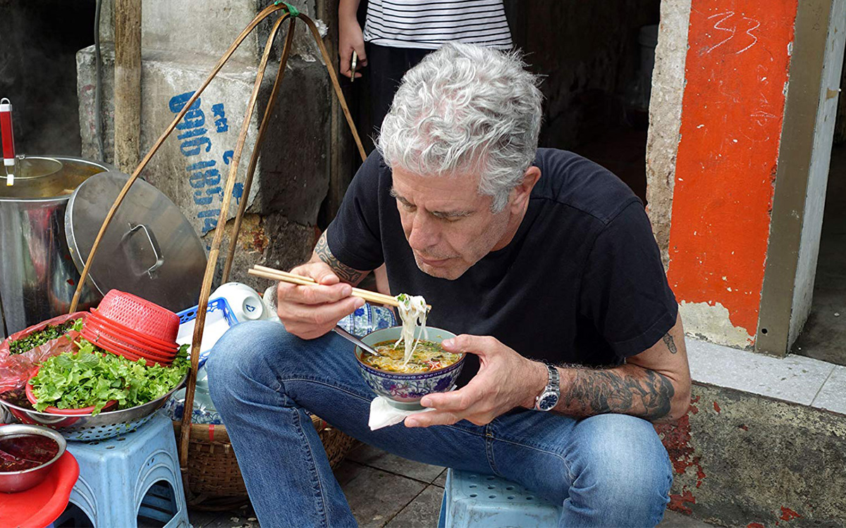 Anthony Bourdain tucking into a bowl of noodles on the set of Parts Unknown, 2013 (Credit: IMDB). 