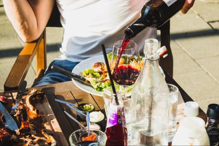 A man pouring wine at a BBQ. (Louis Hansel on Unsplash)