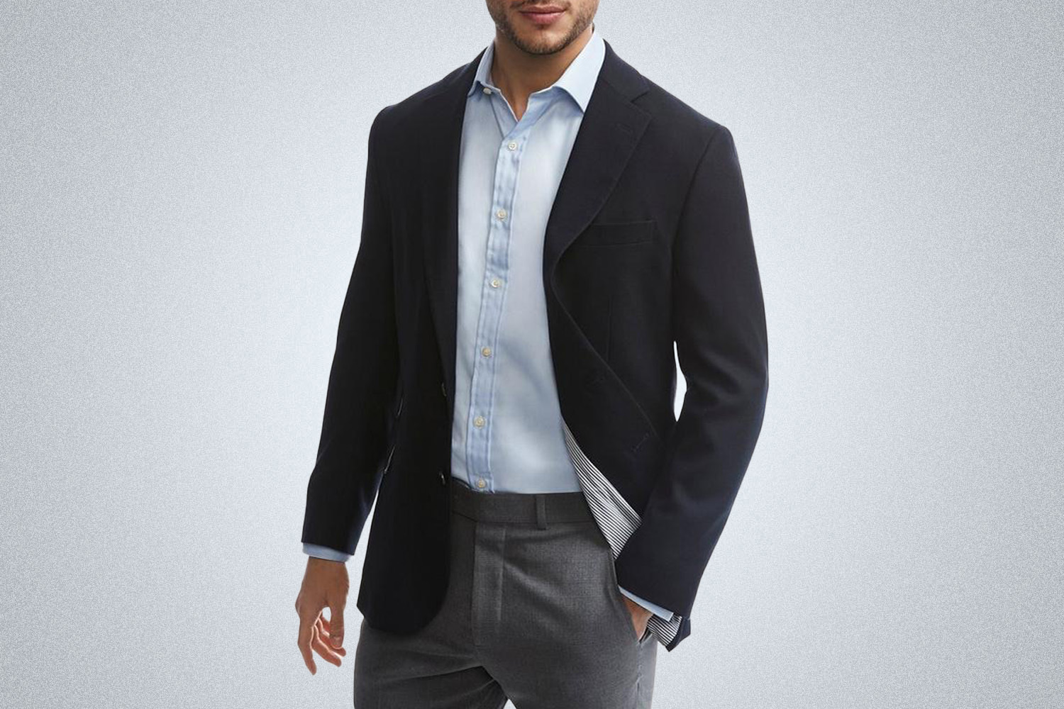 a model in a navy Brooks Brothers travel blazer on a grey background
