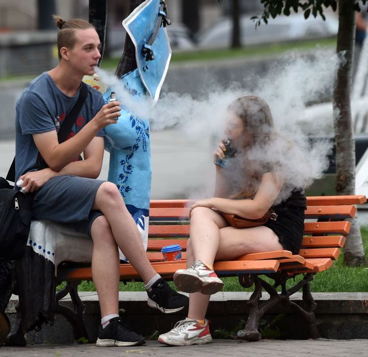 Young people smoke electronic cigarettes as they rest in the center of the Ukrainian capital of Kiev, on August 15, 2019. (Photo by Sergei SUPINSKY / AFP)        (Photo credit should read SERGEI SUPINSKY/AFP/Getty Images)