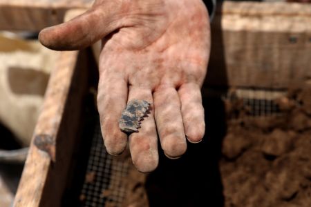 A Palestinian excavator holds on July 16, 2019, a flint stone blade found in the rubble at the archeological excavation site of a settlement from the Neolithic Period (New Stone Age), discovered during archaeological excavations by the Israel Antiquities Authority near Motza Junction, about 5km west of Jerusalem. - The settlement is the largest known in Israel from that period and one of the largest of its kind in the region. (Photo by GALI TIBBON / AFP) 