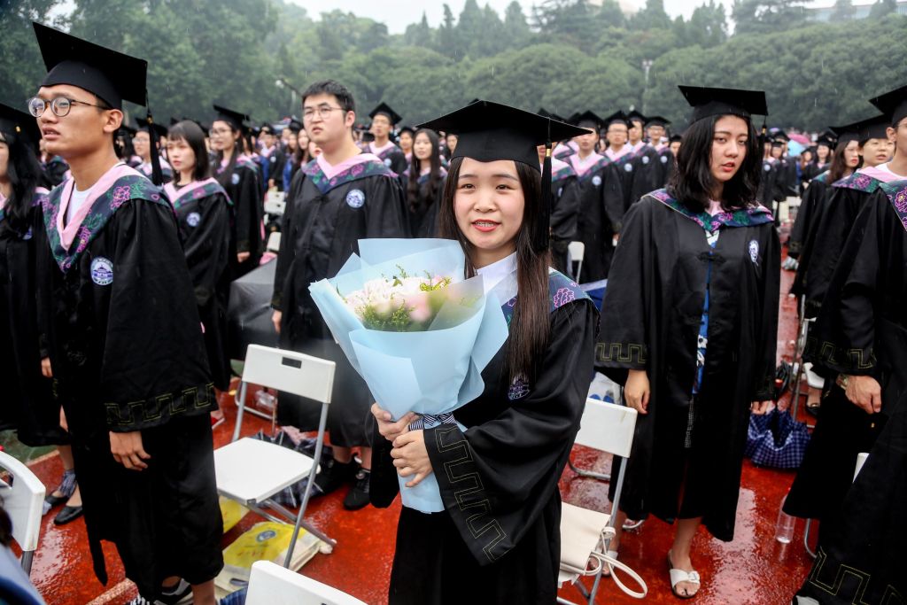 A graduate holding flowers attends the graduation ceremony of Wuhan University with her wife and child on June 22, 2018 in Wuhan, Hubei Province of China. Over 15,000 undergraduates, master and doctoral graduates took part in the commencement ceremony of Wuhan University in the rain on Friday. (Photo by Zhang Chang/China News Service/Visual China Group via Getty Images)